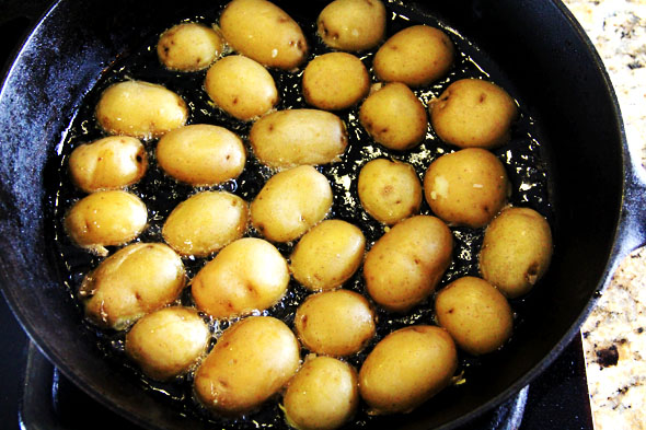 When the oil is hot, arrange the potatoes in a single layer, cut-side down. 