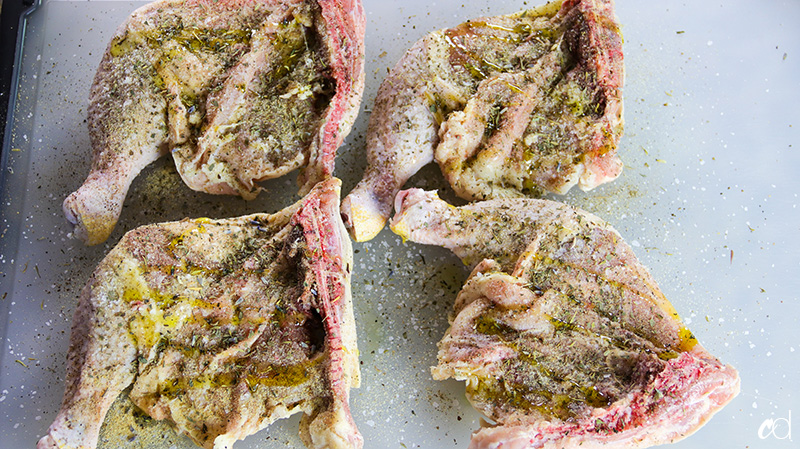 olive oil drizzled over raw seasoned chicken leg quarters