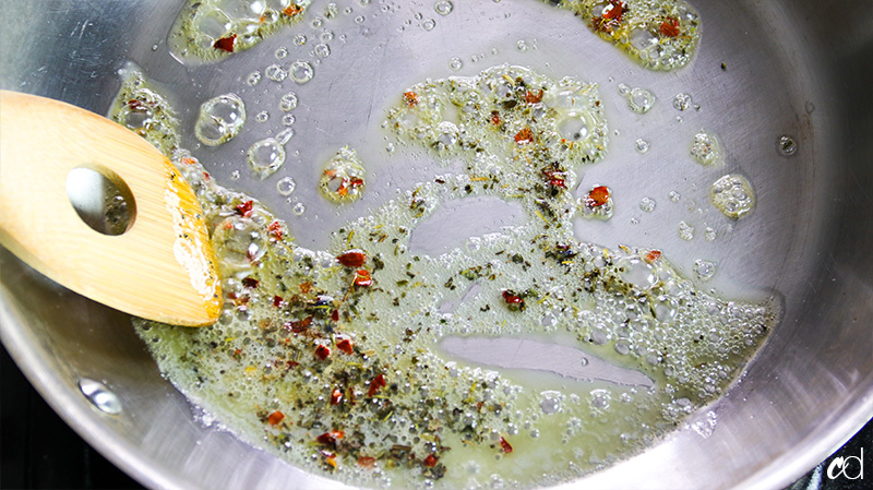 blooming crushed red pepper flakes and herbs de provence in hot butter